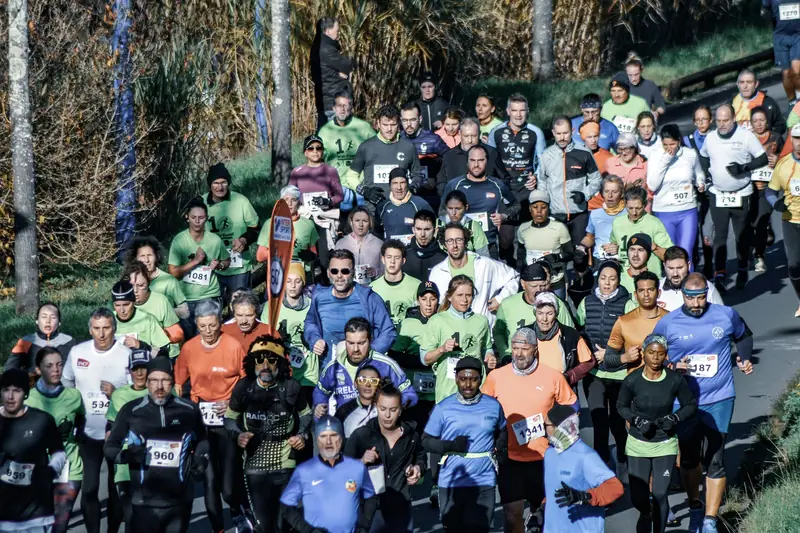 A crowd of runners of all ages wearing race numbers at the start of a community run