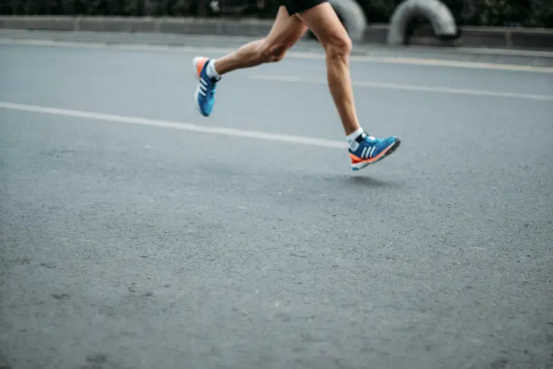 A runner's feet in running shoes, mid-stride on a road