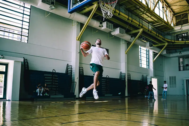 A player taking off from one foot for a layup in an indoor gym