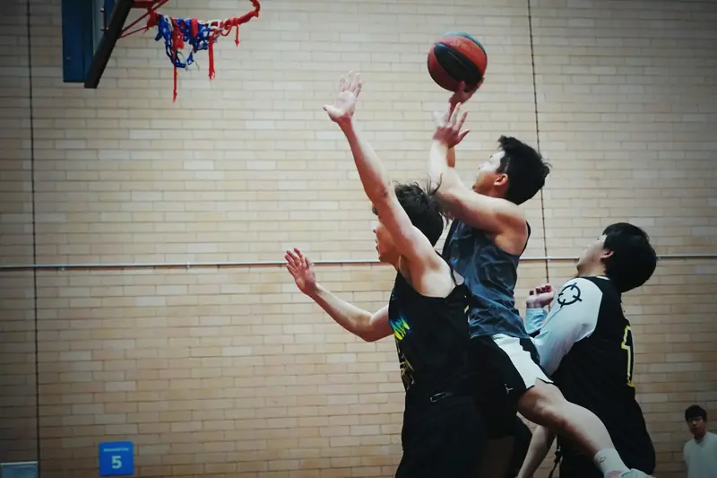 Players jumping together for a rebound under the basket in an indoor gym