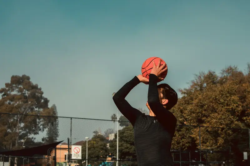 A player on an outdoor court lifting the ball above his head to shoot