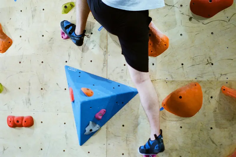 Climbing shoes placed on small holds on an indoor wall, seen from below