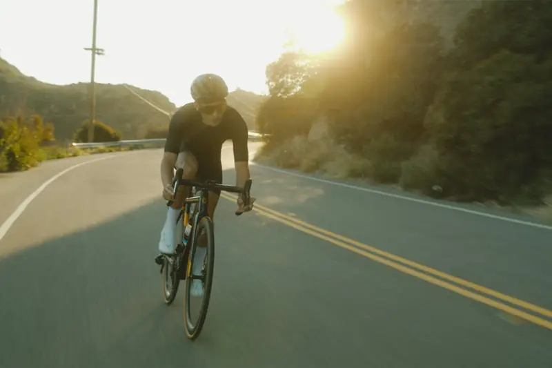 A rider climbing a winding mountain road in low evening sun