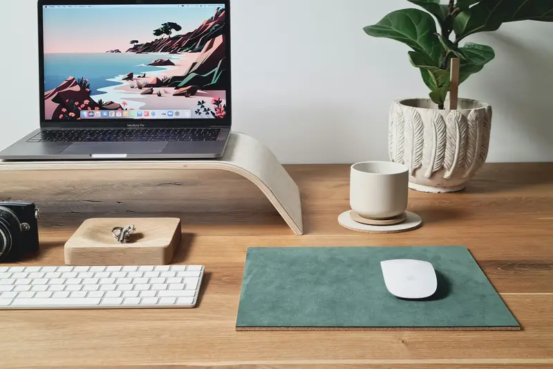 A laptop raised on a stand with a separate keyboard and mouse on a tidy wooden desk