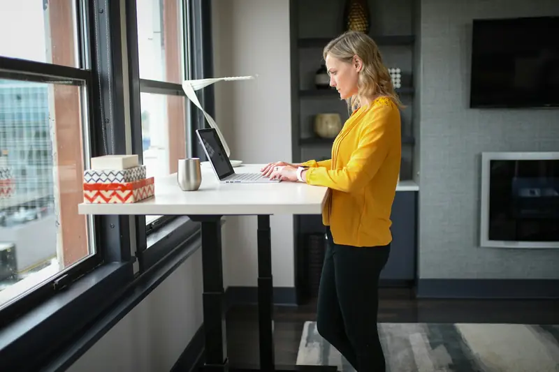 A woman working at a standing desk by a window