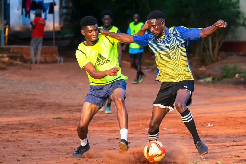 Two players battling for the ball on a dusty pitch