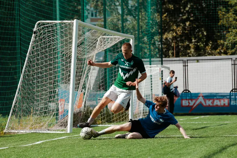 A player shooting at goal as a defender slides in to block