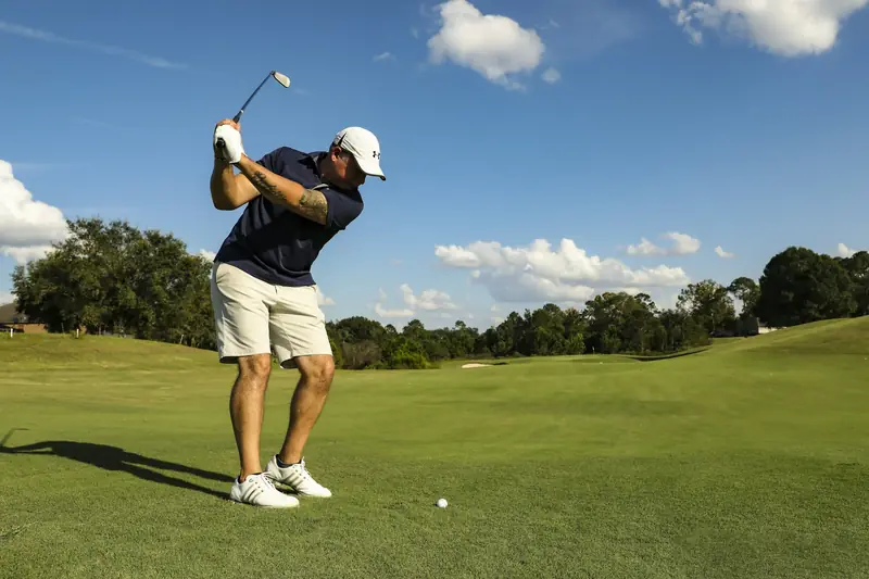 A golfer at the top of the backswing on a sunny course