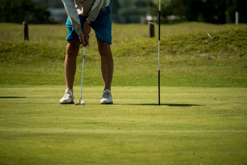 A golfer standing over a putt near the flag