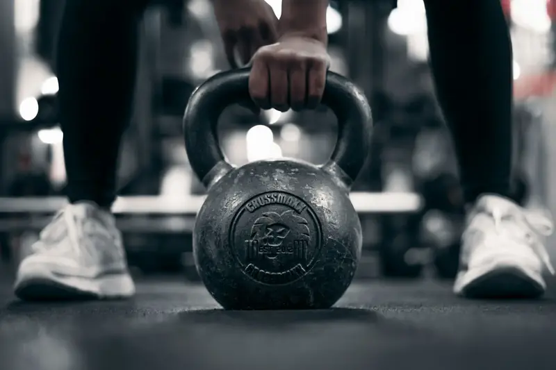 A hand gripping a kettlebell on a gym floor