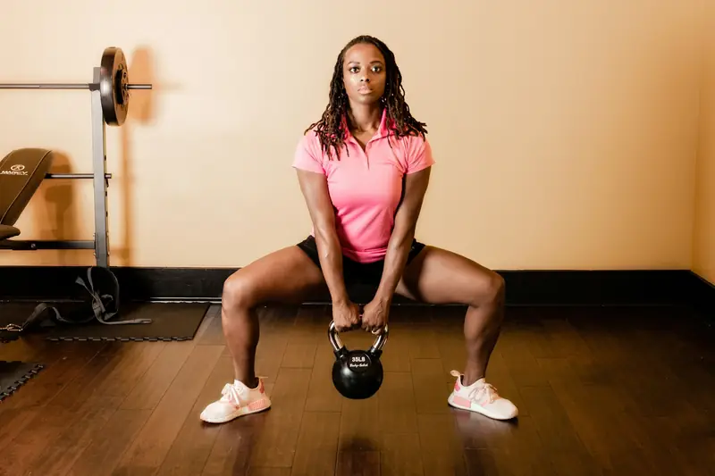 A woman doing a goblet squat with a kettlebell in a gym