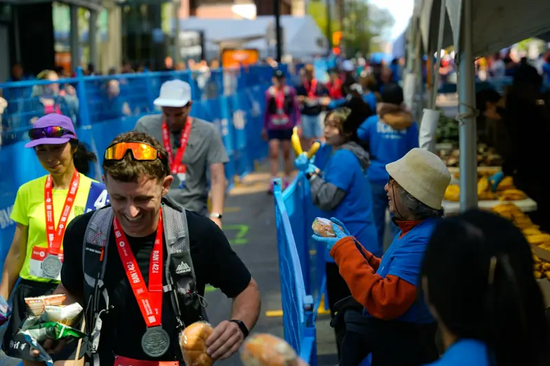 Marathon finishers with medals collecting food and drinks after the race