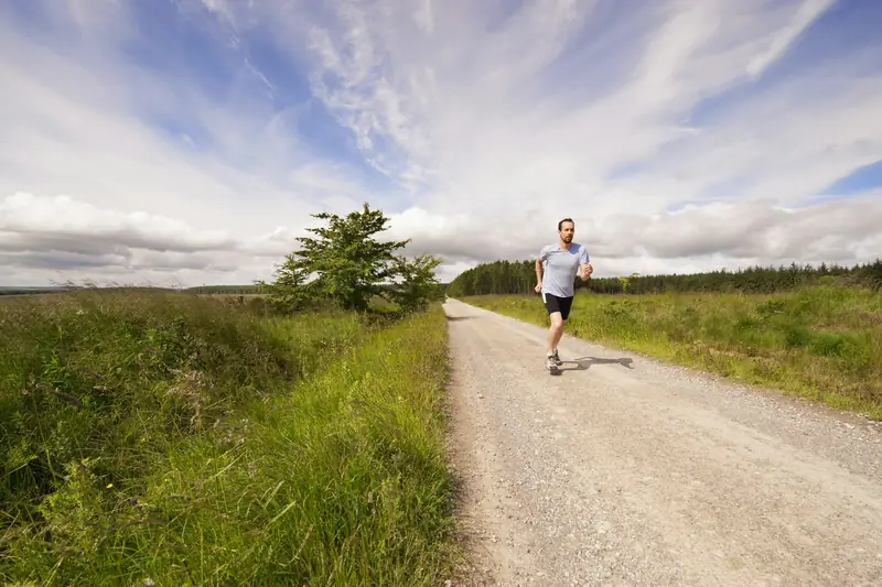 A runner on a long gravel track through open countryside under a big sky