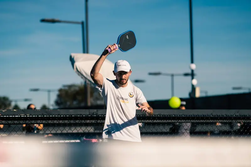 A player reaching up to hit an overhead on an outdoor court
