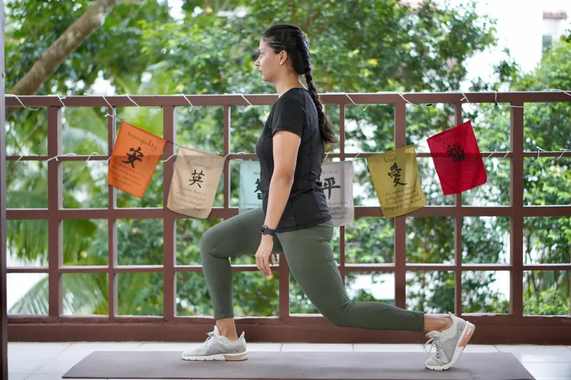 A woman doing a lunge on a mat on a balcony