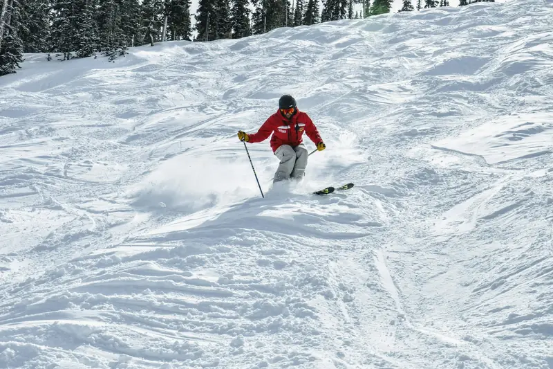 A skier turning through soft, bumpy snow among trees