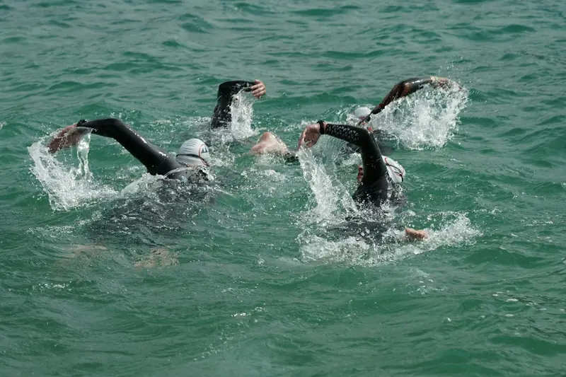 Swimmers in wetsuits swimming close together in open water